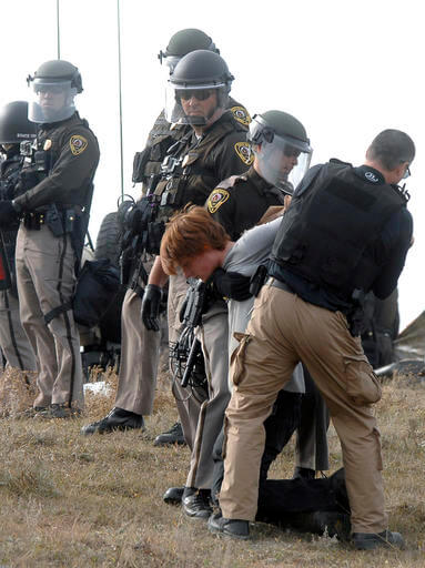An unidentified CANNON BALL Access Pipeline protester is arrested inside the Front Line Camp as law enforcement surround the camp to remove the protesters from the property and relocated to the overflow camp a few miles south of Highway 1806 in Morton County, N.D., Thursday, Oct. 27, 2016. (Mike McCleary/The Bismarck Tribune via AP)